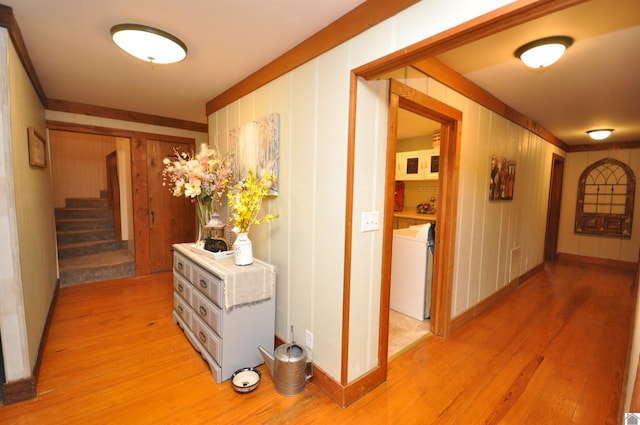 hallway featuring wooden walls, light hardwood / wood-style flooring, and washer / dryer