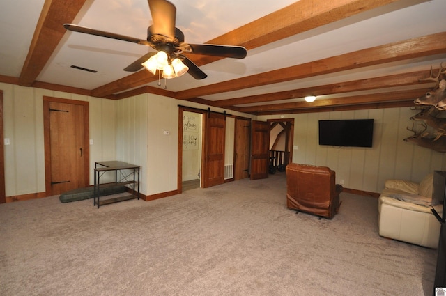 interior space featuring a barn door, ceiling fan, and beamed ceiling