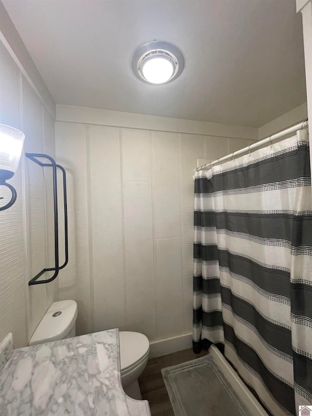 bathroom featuring hardwood / wood-style floors, toilet, and a shower with shower curtain