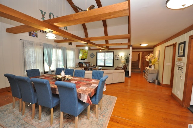 dining space featuring wood-type flooring and vaulted ceiling with beams