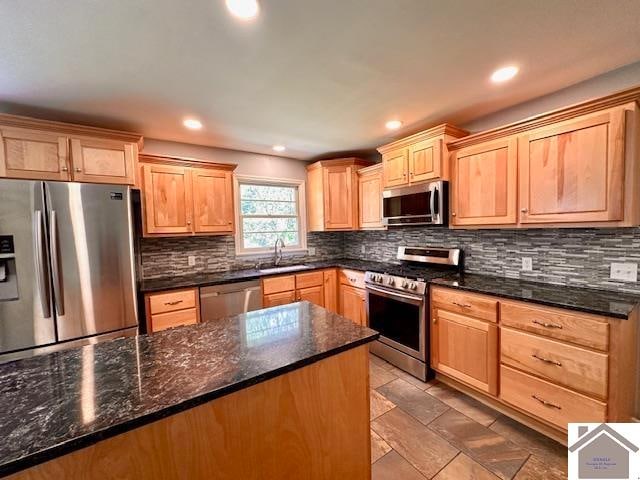 kitchen with appliances with stainless steel finishes, decorative backsplash, dark stone countertops, and sink