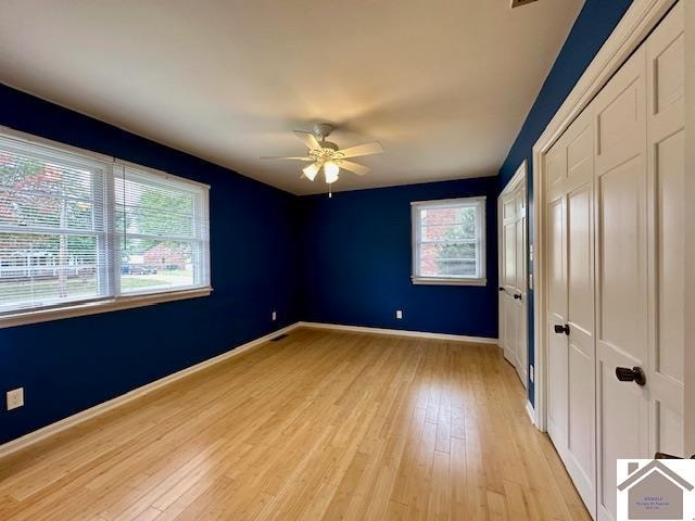 unfurnished bedroom featuring multiple windows, light wood-type flooring, and ceiling fan