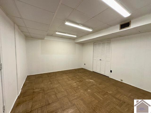 basement featuring a paneled ceiling and dark parquet floors