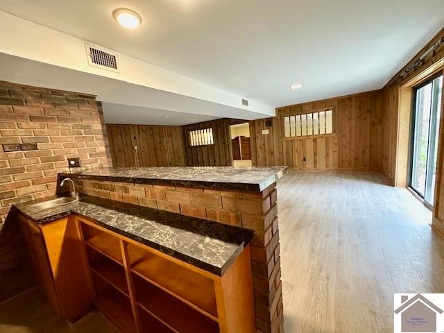 bar with light hardwood / wood-style floors and wooden walls