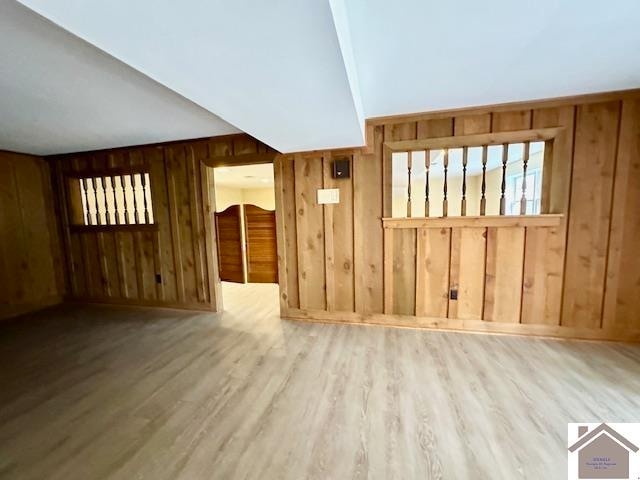 interior space featuring light wood-type flooring and wooden walls