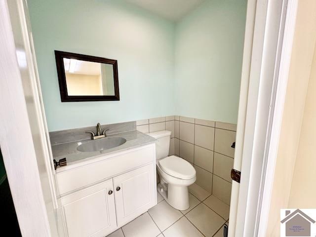 bathroom with tile walls, vanity, toilet, and tile patterned floors