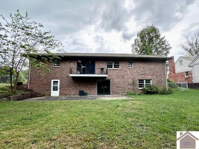 rear view of property featuring a balcony, a yard, and a patio area