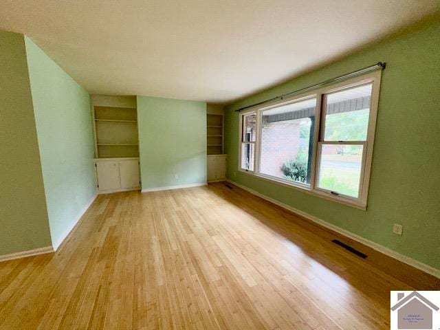 empty room with light hardwood / wood-style flooring and built in features