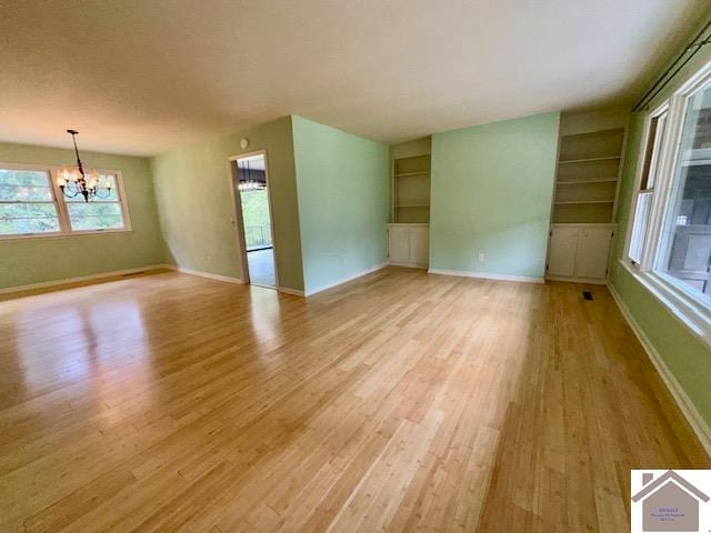 interior space with an inviting chandelier, built in features, and light hardwood / wood-style floors