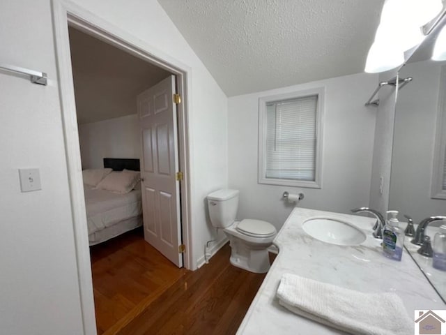 bathroom with vanity, toilet, vaulted ceiling, a textured ceiling, and hardwood / wood-style floors