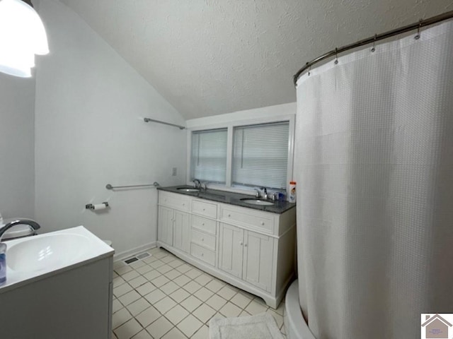 bathroom with tile patterned flooring, a textured ceiling, vaulted ceiling, walk in shower, and vanity