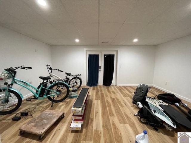 exercise room with wood-type flooring and a paneled ceiling