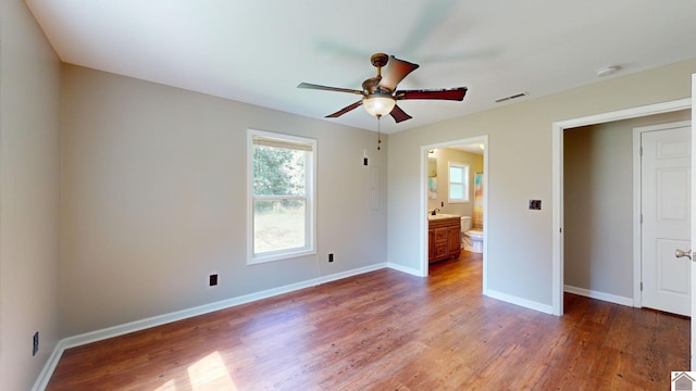 unfurnished bedroom with ensuite bath, ceiling fan, and hardwood / wood-style flooring