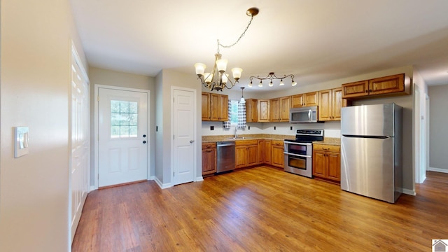 kitchen featuring sink, a notable chandelier, hardwood / wood-style floors, pendant lighting, and appliances with stainless steel finishes