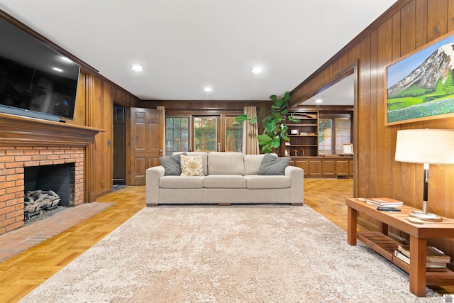 living room with light parquet flooring, crown molding, wood walls, and a brick fireplace