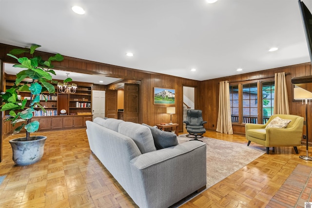 living room featuring light parquet flooring, wood walls, and a notable chandelier