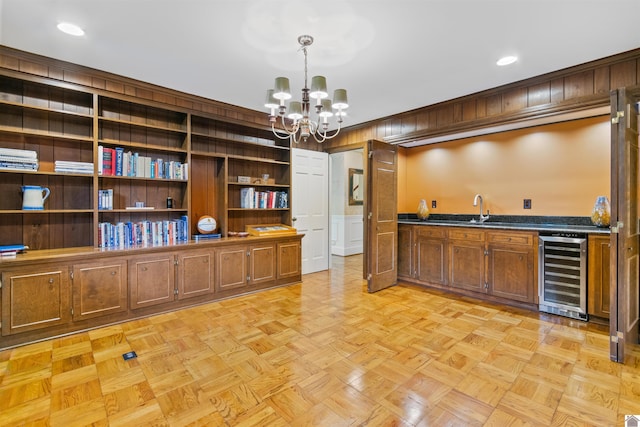 bar with wine cooler, light parquet flooring, pendant lighting, sink, and a chandelier