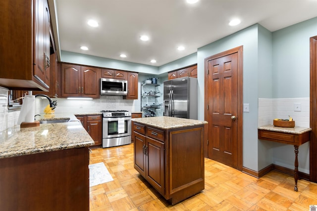 kitchen with light stone counters, appliances with stainless steel finishes, sink, and a kitchen island