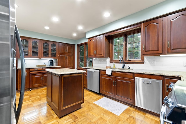 kitchen with stainless steel appliances, sink, light parquet floors, and a kitchen island