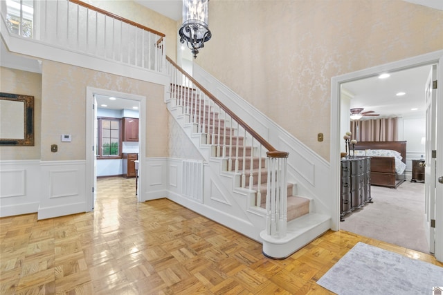 stairway featuring ceiling fan, parquet flooring, and a high ceiling