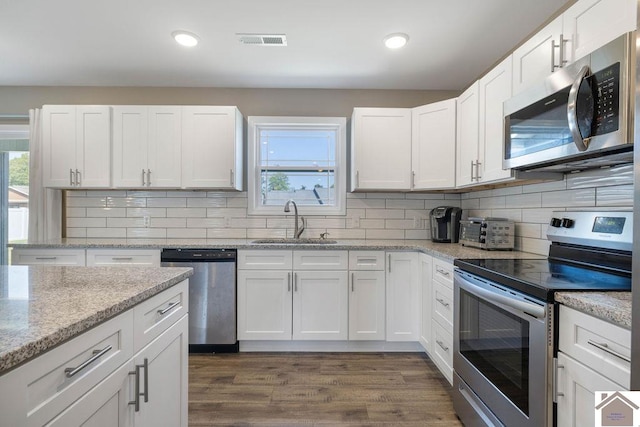 kitchen with appliances with stainless steel finishes, white cabinetry, sink, and dark wood-type flooring