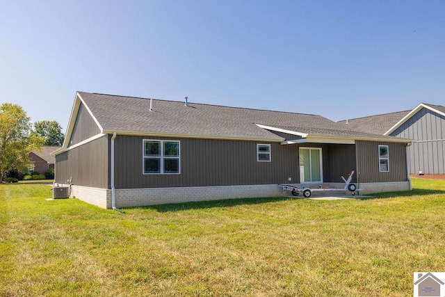 rear view of property with a lawn and central air condition unit