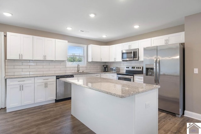 kitchen with stainless steel appliances, white cabinets, a kitchen island, and dark hardwood / wood-style flooring