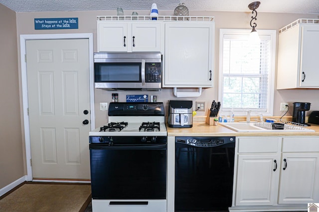 kitchen with black dishwasher, a textured ceiling, white gas stove, white cabinetry, and decorative light fixtures