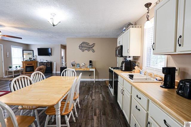 dining space with a textured ceiling, ceiling fan, dark wood-type flooring, and sink