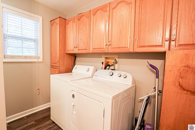 clothes washing area featuring washing machine and clothes dryer, a textured ceiling, cabinets, and dark hardwood / wood-style flooring