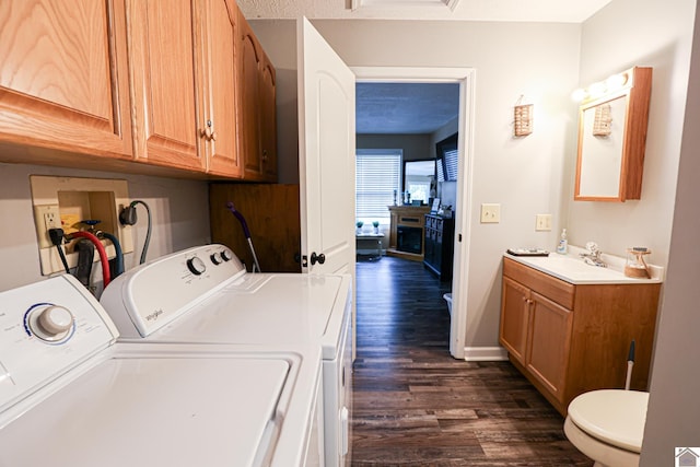 laundry area with dark hardwood / wood-style floors, washer and dryer, and sink