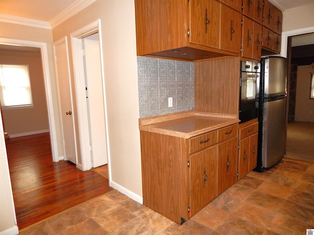 kitchen featuring light wood-type flooring, black oven, crown molding, and stainless steel refrigerator