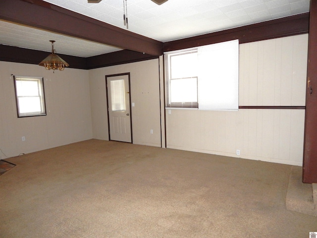 carpeted empty room featuring beam ceiling and wood walls