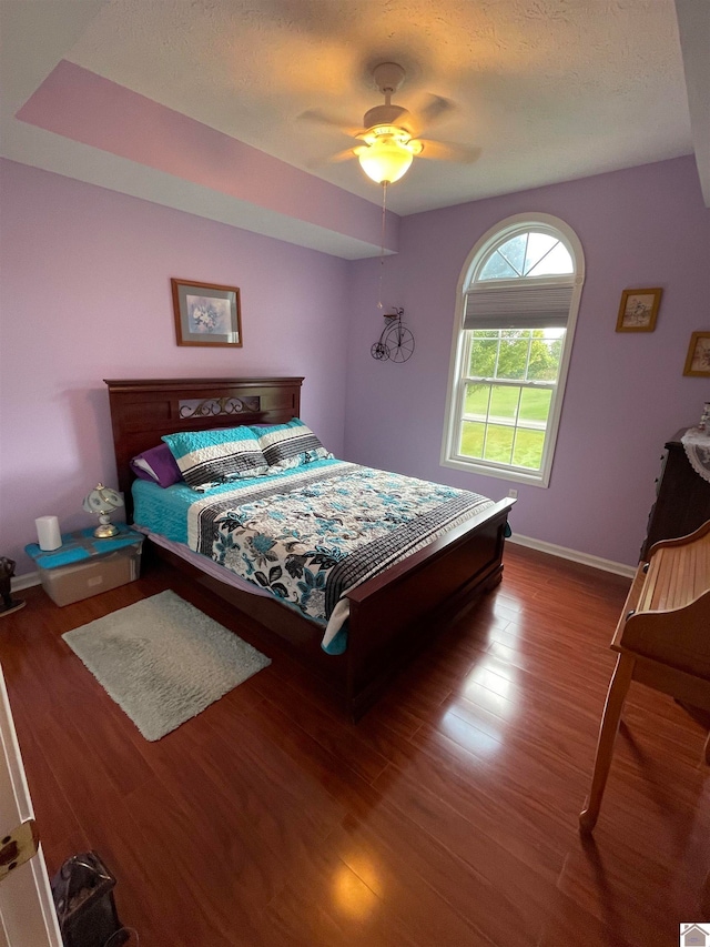 bedroom with ceiling fan, hardwood / wood-style floors, and a textured ceiling