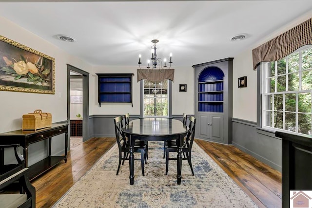 dining room featuring an inviting chandelier, plenty of natural light, and dark hardwood / wood-style flooring