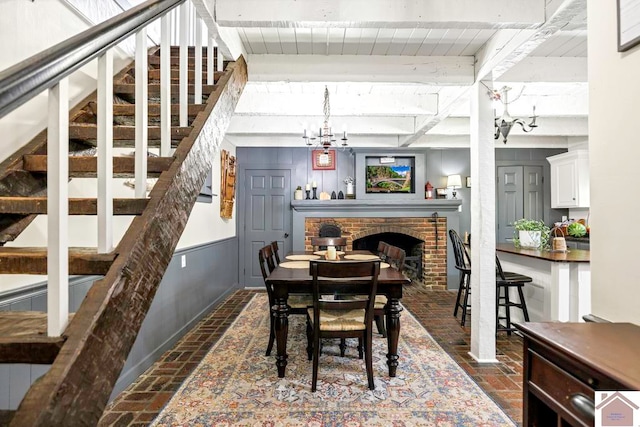 dining space with beamed ceiling, a fireplace, and a notable chandelier