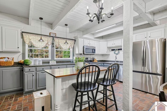 kitchen with gray cabinets, a chandelier, white cabinets, beam ceiling, and appliances with stainless steel finishes