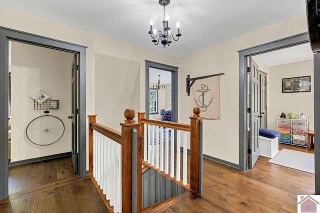 hallway with hardwood / wood-style floors and a notable chandelier