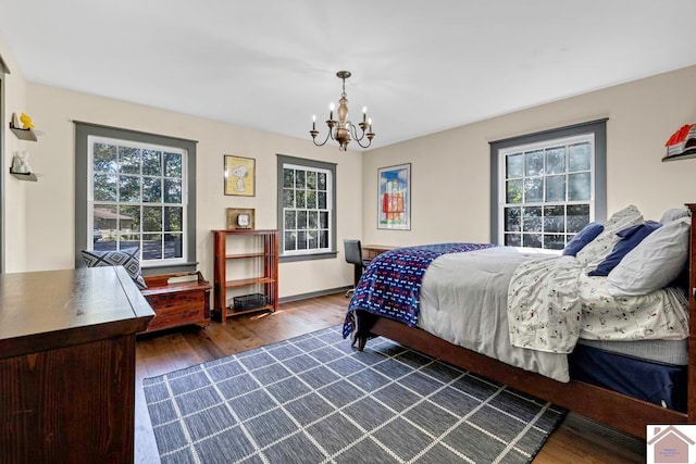 bedroom with multiple windows, an inviting chandelier, and dark hardwood / wood-style floors