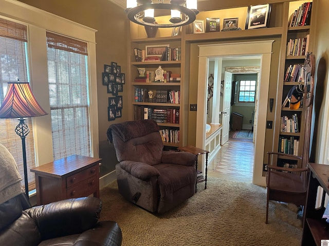 sitting room featuring a notable chandelier, hardwood / wood-style floors, a healthy amount of sunlight, and built in features