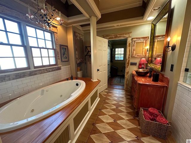 bathroom with a bathtub, an inviting chandelier, crown molding, vanity, and toilet