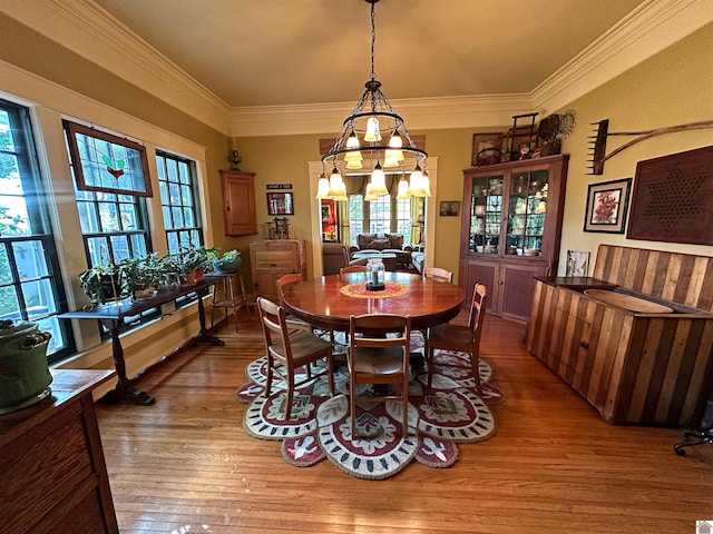 dining room featuring an inviting chandelier, wood-type flooring, plenty of natural light, and ornamental molding