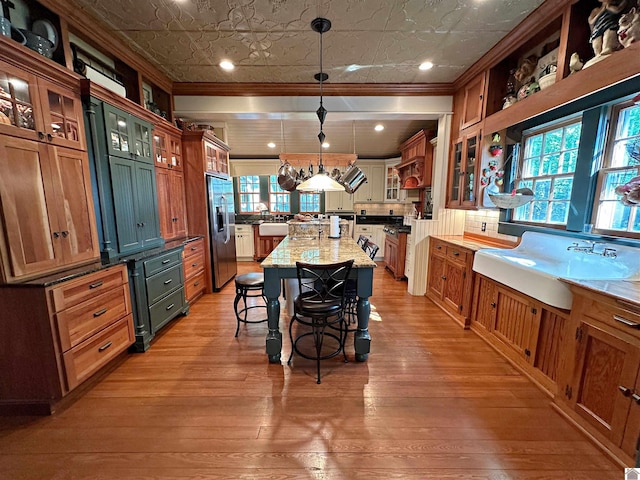 kitchen featuring light hardwood / wood-style flooring, hanging light fixtures, stainless steel fridge, and a wealth of natural light