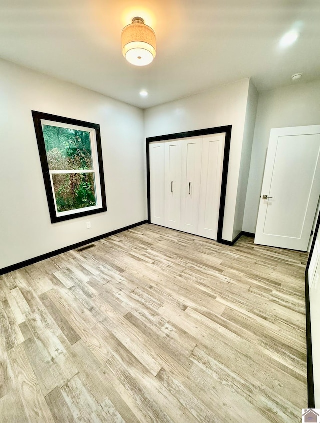 unfurnished bedroom with a closet and light hardwood / wood-style flooring