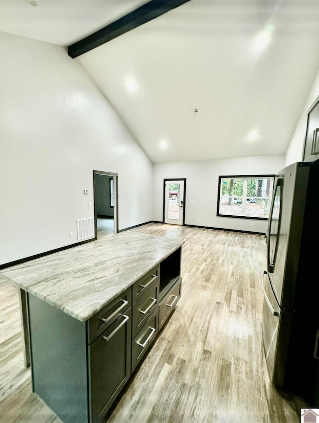 kitchen with light wood-type flooring, light stone counters, a kitchen island, vaulted ceiling with beams, and refrigerator