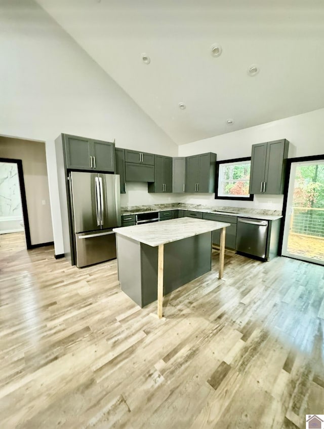 kitchen featuring light hardwood / wood-style flooring, stainless steel appliances, high vaulted ceiling, and a kitchen island