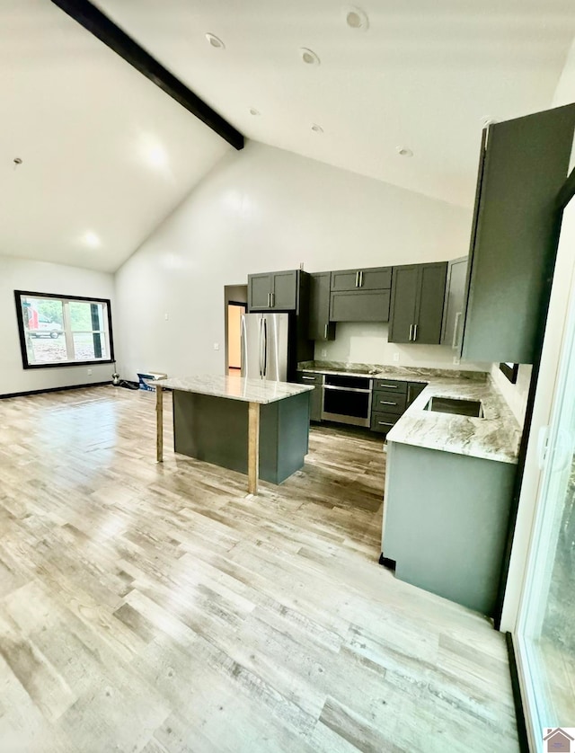 kitchen with light stone counters, light hardwood / wood-style floors, a center island, and stainless steel refrigerator