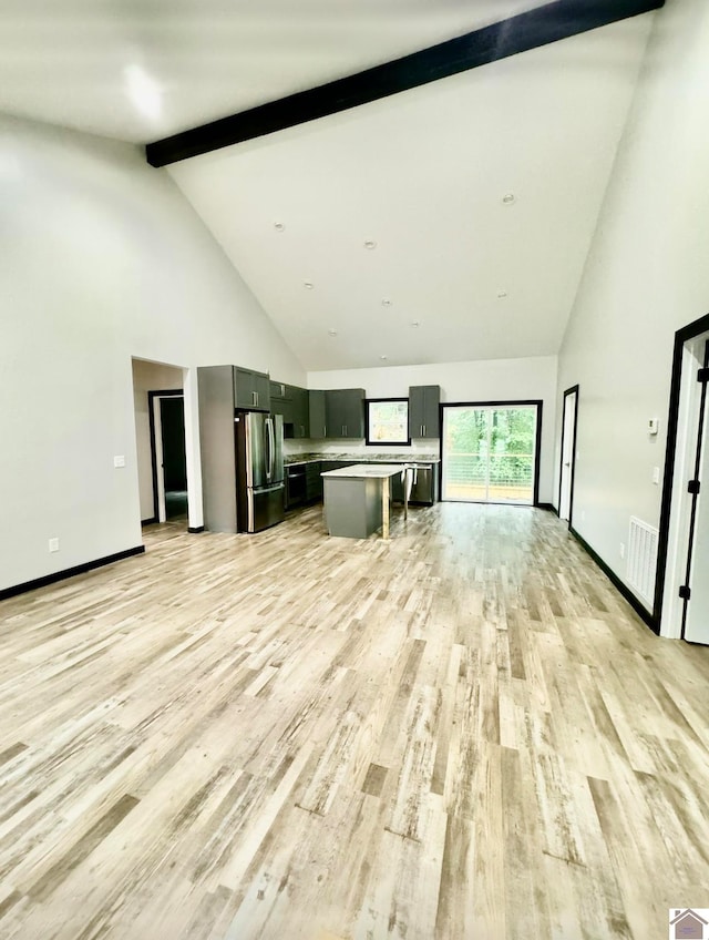 unfurnished living room with high vaulted ceiling, beam ceiling, and light hardwood / wood-style flooring