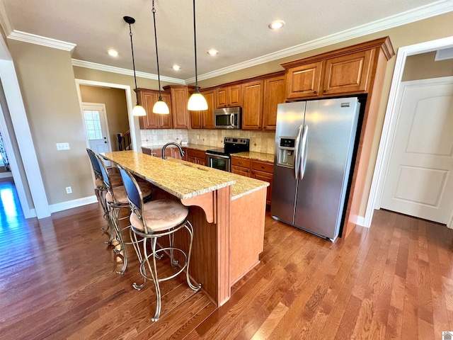 kitchen featuring light stone counters, a kitchen island with sink, stainless steel appliances, decorative light fixtures, and dark hardwood / wood-style flooring