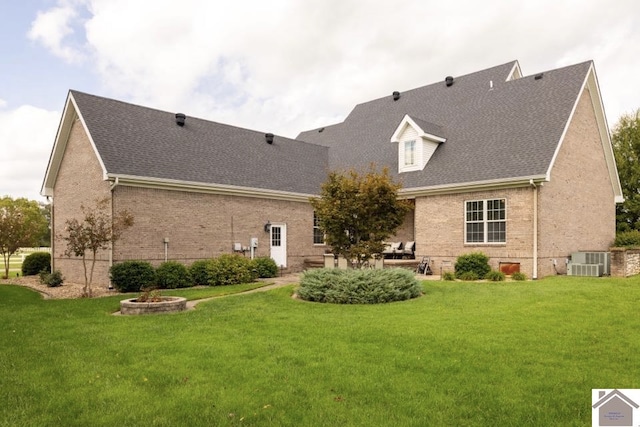 rear view of house featuring a fire pit, a lawn, and central air condition unit